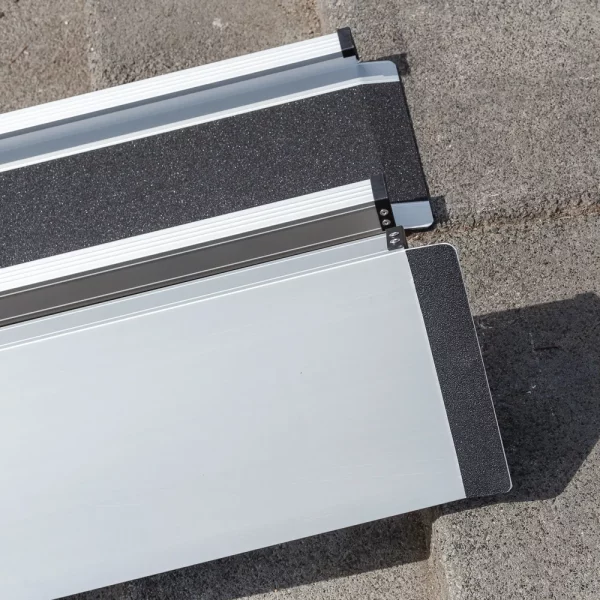 Detailaufnahme der Gummierung der oberen Auflage zweier Rollstuhlrampenschienen die parallel zueinander auf eine Betonfläche aufgestellt sind.